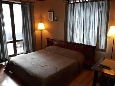 a bedroom with a bed and a desk and windows at Family Hotel Pchelina in Rilski Manastir
