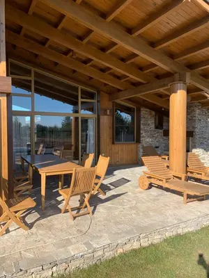 a patio with a table and chairs and a wooden roof at House in Pirin Golf Bansko in Razlog