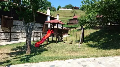 a playground with a red slide and a tree at Panorama Family Hotel in Zlatograd