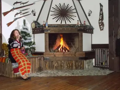 a woman standing in front of a fireplace at Panorama Family Hotel in Zlatograd
