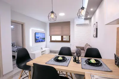 a dining room and living room with a table and chairs at Babylon Park Apartment in Sandanski