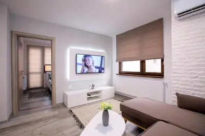 a living room with a couch and a tv on a wall at Babylon Park Apartment in Sandanski