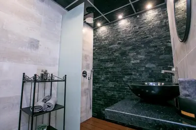a bathroom with a sink and a stone wall at Babylon Park Apartment in Sandanski