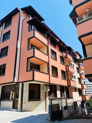 a orange building with black windows on a street at Babylon Park Apartment in Sandanski