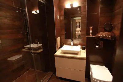 a bathroom with a sink and a mirror and a shower at Brown Cottage Apartment in Sofia
