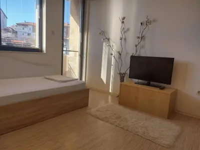 a living room with a flat screen tv on a wooden stand at Apartament Emi in Sandanski