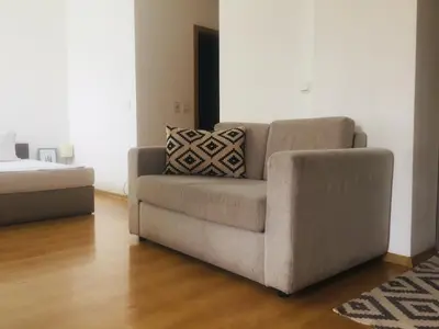 a couch sitting in a living room next to a bed at Fantastic Studio Studentski Grad in Sofia