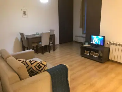 a living room with a couch and a tv and a table at Fantastic Studio Studentski Grad in Sofia