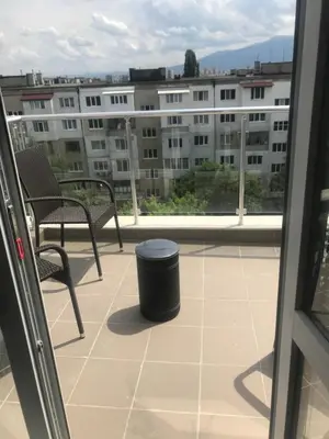 a balcony with a trash can and chairs and a building at NORTH PARK SUITE in Sofia