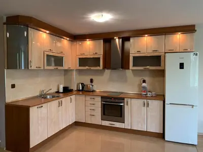 a kitchen with wooden cabinets and a white refrigerator at Apartment City Park Sandanski in Sandanski