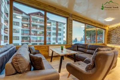 a living room with leather furniture and a large window at Aparthotel Forest Nook in Pamporovo