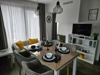 a living room with a table and chairs and a television at Sunny Apartment in Blagoevgrad