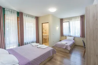 a hotel room with two beds and windows at Къща за гости Перуника in Sapareva Banya