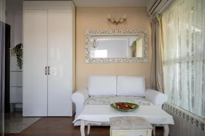 a living room with a white couch and a mirror at Sunny Studio with a view in TOP Center in Sofia