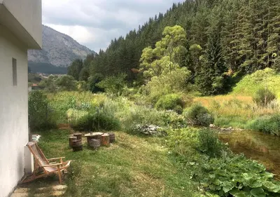 a view of a garden with a river and trees at Къща край реката - Триград in Trigrad
