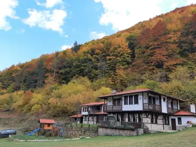 an old house with a playground in front of a mountain at Къща за гости 