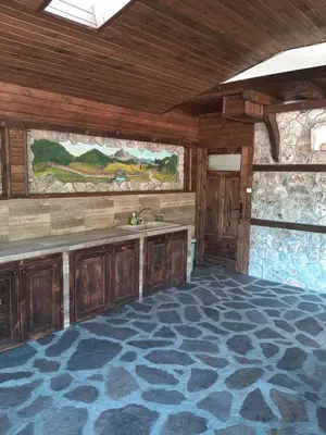 a kitchen with wooden cabinets and a sink in a room at Къща за гости 
