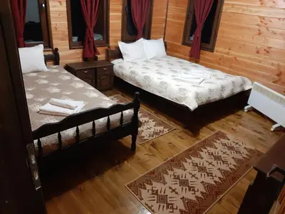 two beds in a room with wooden walls at Къща за гости 