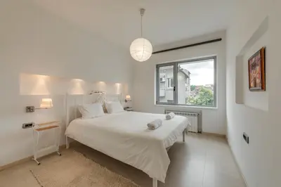 a white bedroom with a large bed and a window at Top Center Apartment next to Vitosha Boulevard in Sofia