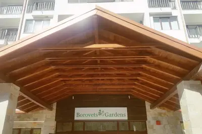 a building with a wooden roof in front of a building at Borovets Holiday Homes in Borovets
