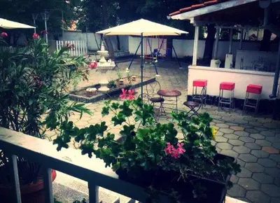 a patio with some plants and chairs and an umbrella at Hotel Shterev Sopot in Sopot