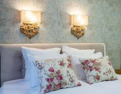 a bed with pillows and two lights on a wall at Paradise Center Premium Suite 1 in Sofia
