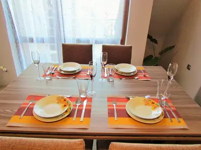 a wooden table with plates and silverware on it at Апартамент за гости Dolce Vita in Gyurgevo