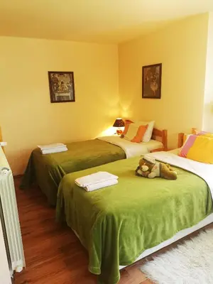 a bedroom with two beds with green sheets and a teddy bear sitting on top at Къщата на Румен in Sofia
