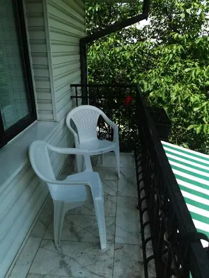 two white chairs sitting on the porch of a house at Къщата на Румен in Sofia