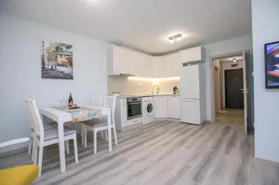 a kitchen with white cabinets and a table and chairs at The Sun loves You - right beside the Park! in Sandanski