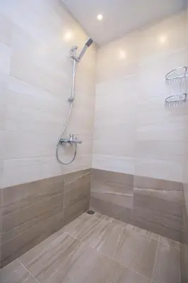 a shower in a bathroom with wooden walls at The Sun loves You - right beside the Park! in Sandanski
