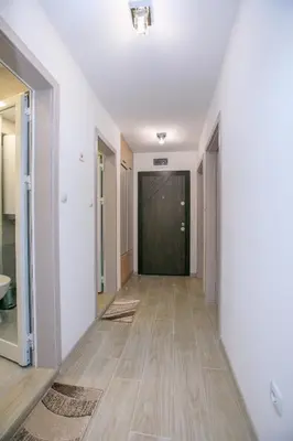 an empty hallway with a wooden floor and a black door at The Sun loves You - right beside the Park! in Sandanski