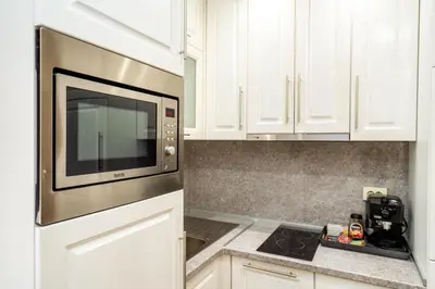 a kitchen with white cabinets and a microwave at Park Apartment Emilin in Sandanski