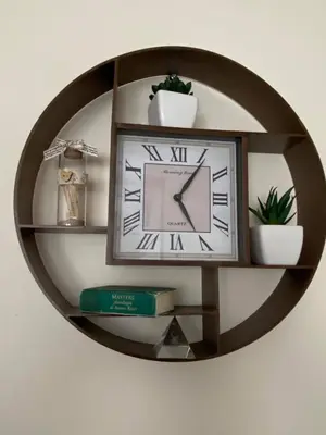 a clock on a wall with a shelf with plants at Studio Anastasia in Sapareva Banya