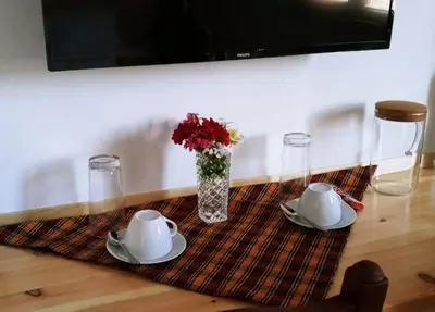 a table with two plates and a vase of flowers at Родопчани Старцево in Starzewo
