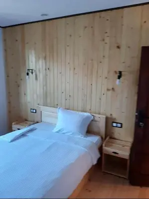 a bedroom with a white bed and wooden walls at Родопчани Старцево in Starzewo
