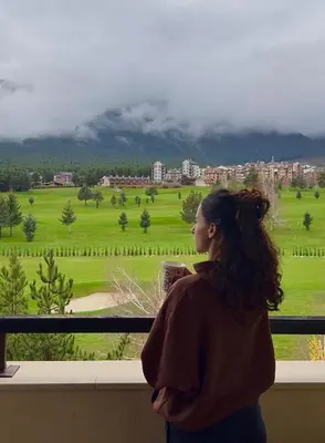 a woman standing in a balcony looking out at a city at Sunny Duplex, Mountain Views, Spa Access, Near Bansko, Terra Complex in Razlog
