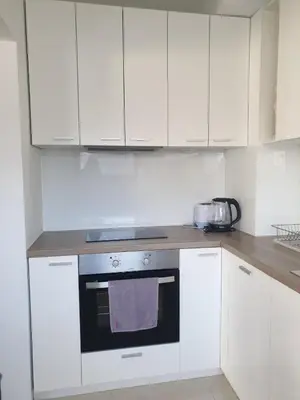 a kitchen with white cabinets and a stove top oven at Апартамент Перла in Sandanski