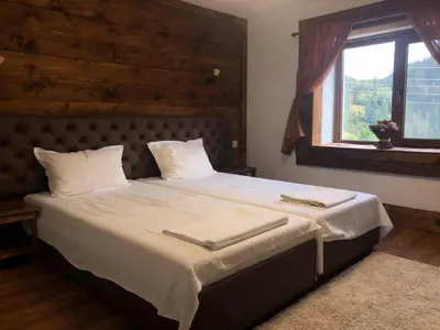 a bedroom with a large bed with white sheets and a window at Къща за гости Виевци in Vievo