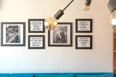 a group of framed pictures on a wall with a blue couch at ОРФЕЕВИТЕ ПЕСНИ in Devin