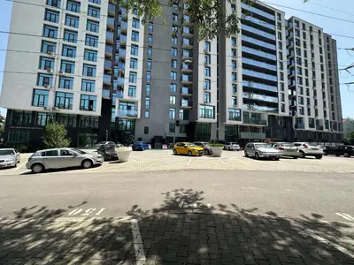 a parking lot with cars parked in front of a large building at Boutique Magenta Gold Apartment in Sofia