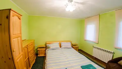 a small green bedroom with a bed and a window at Къща за гости Черна река in Ribarica