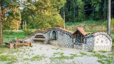 a small building with a bench and a table at Къща за гости Черна река in Ribarica
