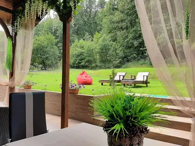 a screened in porch with a view of a garden at Вила МАЯ in Krayni Dol