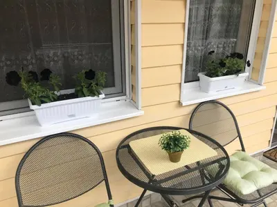 two chairs and a table on a porch with two windows at Vega Apartment in Velingrad