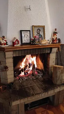 a fireplace with a fire in the middle of it at Къща за гости Каневи in Momchilovtsi