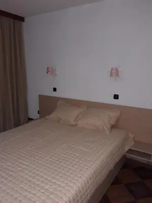 a bed in a bedroom with two lights on the wall at Къща за гости Динас in Zmeitsa