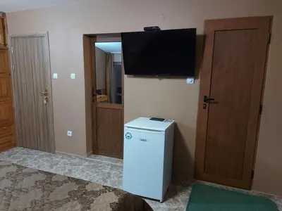 a room with a small refrigerator and a television on the wall at Вила Сладък Живот in Tsigov Chark