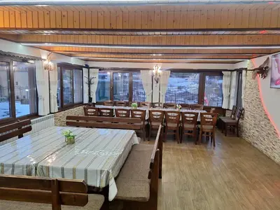 a dining room with tables and chairs and windows at Perla in Dospat