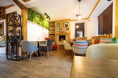 a restaurant with tables and chairs and a fireplace at Seven Springs Hotel in Banya
